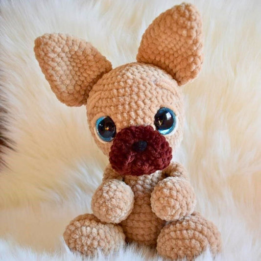 Crocheted dog toy with blue eyes and a brown nose on a fluffy white background